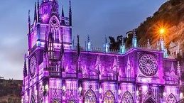 a temple church lighted in purple and blue, blue sky exterior building las lajas